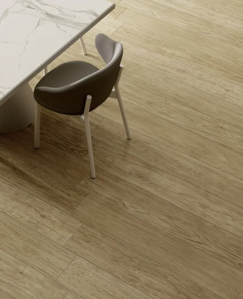 
A modern dining table with a white marble top and a single black chair with white legs on a wooden floor, reminiscent of a gentle stream. The table is partially visible, and the light brown wood flooring features a natural grain pattern.